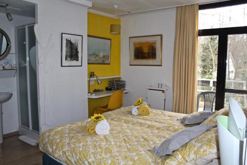 een slaapkamer met een bed met gele muren en een bureau bij Linden-Jachthoorn in Lubbeek