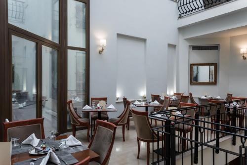 a restaurant with tables and chairs and windows at Capsis Bristol Boutique Hotel in Thessaloniki