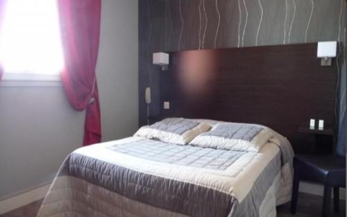 a bedroom with a bed with a wooden head board at Logis Hôtel de la Tour in Masseret