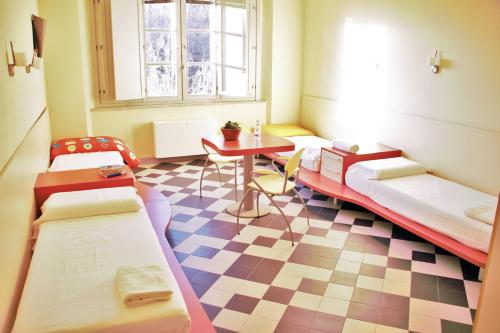 a room with three beds and a table and a table at Ostello La Miniera in Massa Marittima