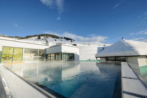 a swimming pool in front of a building with a mountain at Hotel Jennys Schlössl in Serfaus
