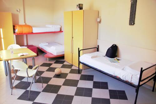 a room with two beds and a table and a desk at Ostello La Miniera in Massa Marittima