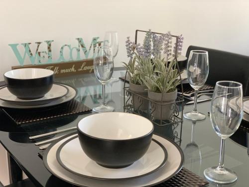 a table with a bowl and plates and wine glasses at Eskdaill Place Apartment in Kettering