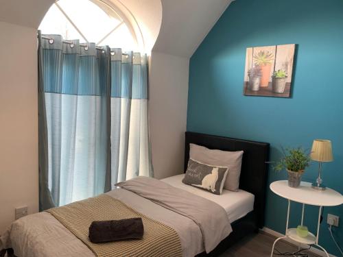 a bedroom with a bed with blue walls and a window at Eskdaill Place Apartment in Kettering