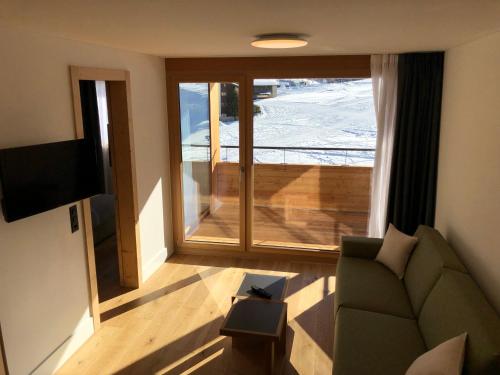 a living room with a couch and a large window at Catrina Resort in Disentis