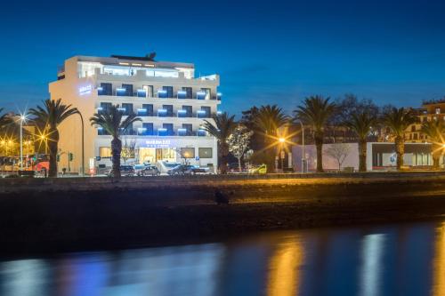 a building with palm trees next to a body of water at Hotel Marina Rio in Lagos