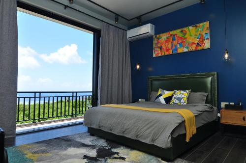 sypialnia z niebieskimi ścianami i łóżkiem z dużym oknem w obiekcie Saipan Skyline Designers Hotel w mieście Saipan