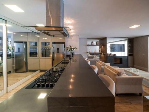 uma grande cozinha com uma mesa longa e um fogão em Residencial Via Florida 03 dormitórios em Gramado