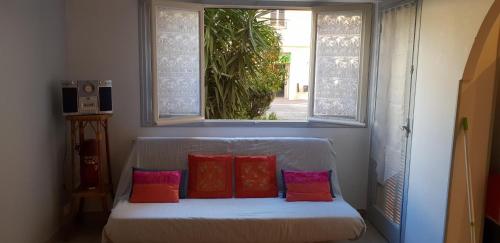 a white couch with four pillows sitting under a window at location saisonnière in Menton