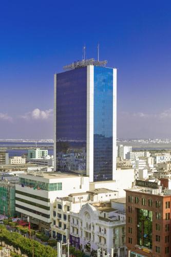 a tall building with a lot of windows in a city at El Mouradi Hotel Africa Tunis in Tunis
