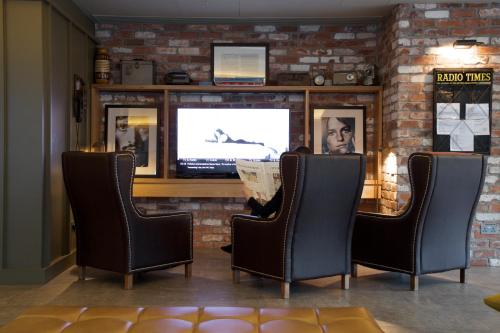 a person sitting in a chair in front of a tv at Bermondsey Square Hotel - A Bespoke Hotel in London