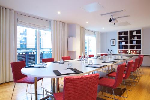 a large dining room with a long table and red chairs at Bermondsey Square Hotel - A Bespoke Hotel in London