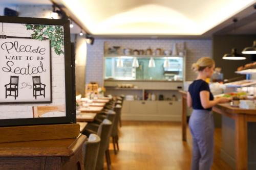 a woman standing at a counter in a restaurant at Bermondsey Square Hotel - A Bespoke Hotel in London