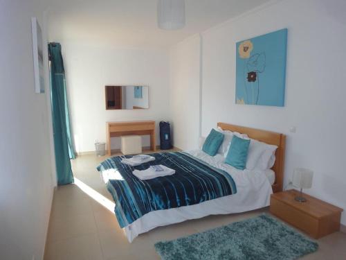 a bedroom with a bed with blue pillows and a rug at Apartamento Ria Formosa no Mar in Fuzeta