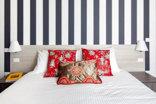 a bed with red pillows and black and white stripes at Laguna Boutique Apartments in Mestre