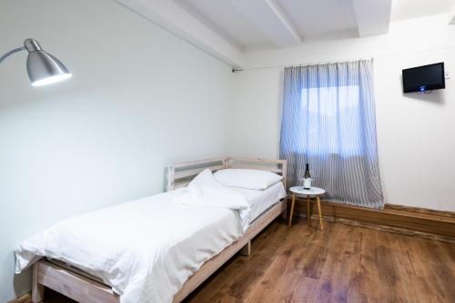 a white bedroom with a bed and a window at Slavia penzion in Mikulov