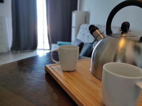 a tea kettle and two cups on a wooden table at Studio Gio - Paraiso del Sur in Playa Paraiso