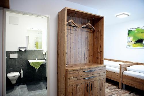 a bathroom with a wooden cabinet next to a toilet at Hotel "City Rooms Wels" in Wels