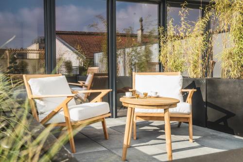two chairs and a table on a patio at Les Suites 7 Anges - Parking, Vue Cathédrale & Centre Historique Reims in Reims