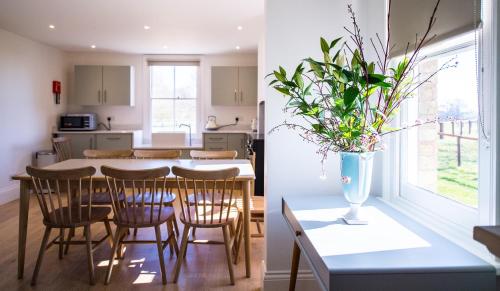 a kitchen and a dining room with a table and chairs at Longstowe Farmhouse in Long Stowe