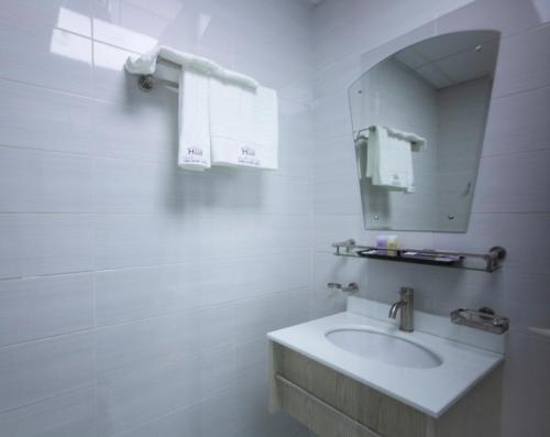 Baño blanco con lavabo y espejo en Home Station Hotel en Mascate