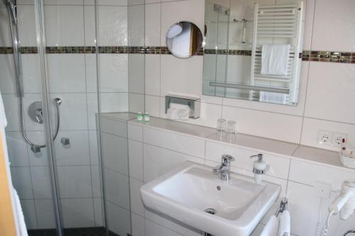 a white bathroom with a sink and a shower at Dohlmühle Hotel & Weingut in Flonheim