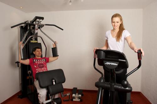 a man and a woman standing next to a exercise bike at Wellnesshotel Mitterwirt in Dienten am Hochkönig