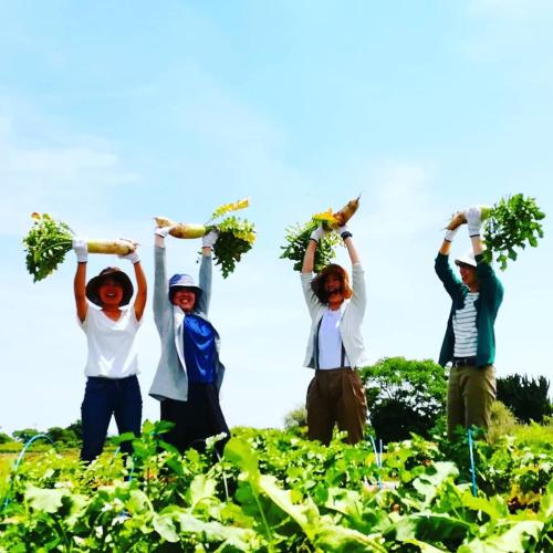 a group of people holding up their crops in a field at COCORETO The Guesthouse Daikon Island in Matsue