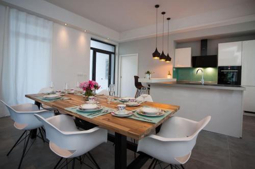 a dining room with a wooden table and white chairs at Villa R&B in Sutivan