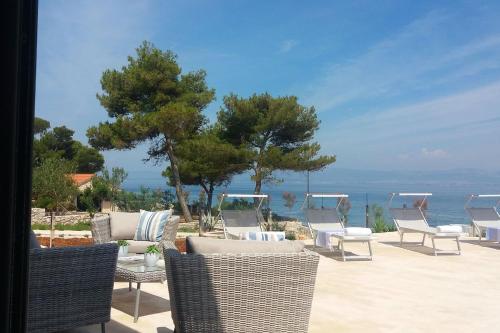 a group of chairs and tables on a patio overlooking the ocean at Villa R&B in Sutivan