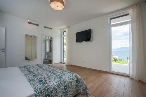 a white bedroom with a bed and a large window at Villa R&B in Sutivan