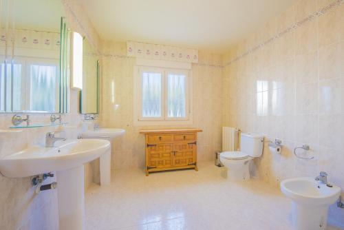 a bathroom with two sinks and a toilet and a window at Villa Gran Sol in Calpe