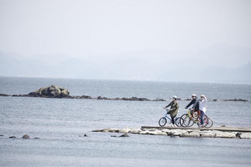 three people riding bikes on a dock in the water at COCORETO The Guesthouse Daikon Island in Matsue