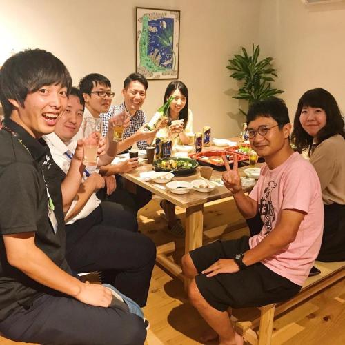 a group of people sitting around a table eating at COCORETO The Guesthouse Daikon Island in Matsue