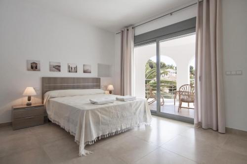 a white bedroom with a bed and a large window at Villa Paz in Benissa
