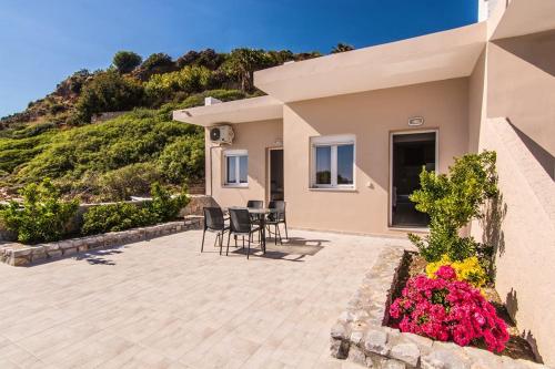 a house with a patio with chairs and flowers at Votsalo Studios & Apartment in Frangokastello