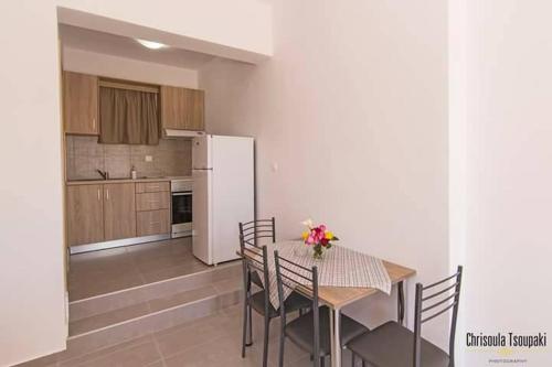 een keuken met een tafel en stoelen en een witte koelkast bij Votsalo Studios & Apartment in Frangokastello