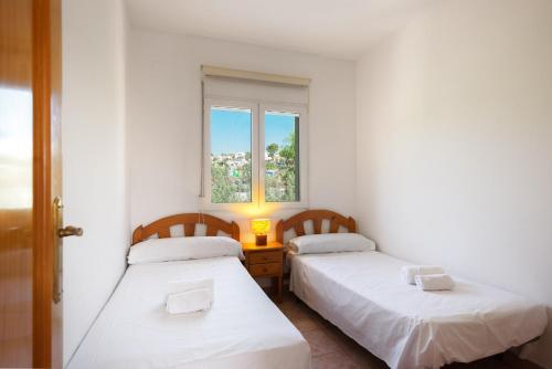 2 camas en una habitación pequeña con ventana en Villa Murano, en Benissa