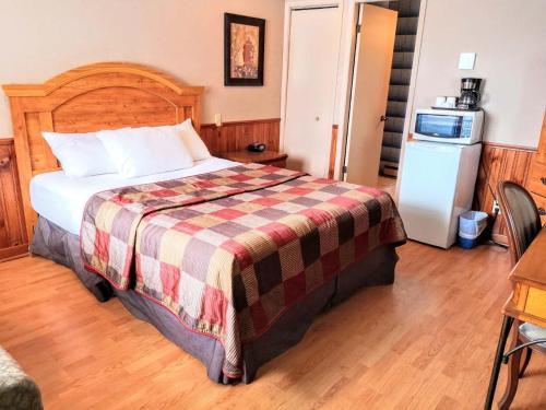 a bedroom with a large bed and a refrigerator at Hotel Motel La Marquise in Sherbrooke