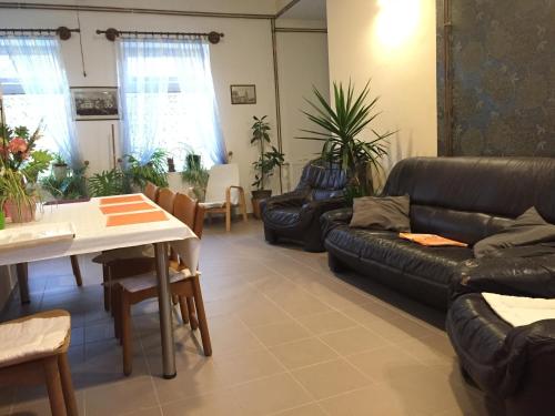 een woonkamer met een zwarte leren bank en een tafel bij Harang Panzió in Gyomaendrőd