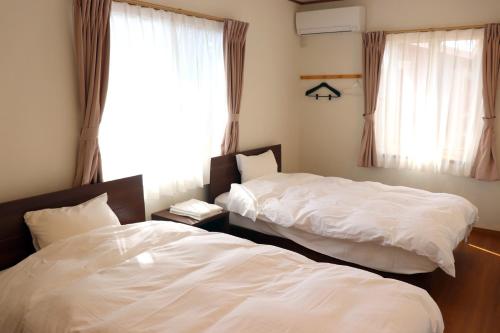 two beds in a room with a window at The Hirosawa City Dome House West Building / Vacation STAY 18763 in Chikusei