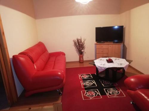 a living room with a red chair and a table at Gitta Nyaralohaz in Gyomaendrőd