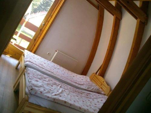 a wooden bed in a room with a window at Gitta Nyaralohaz in Gyomaendrőd