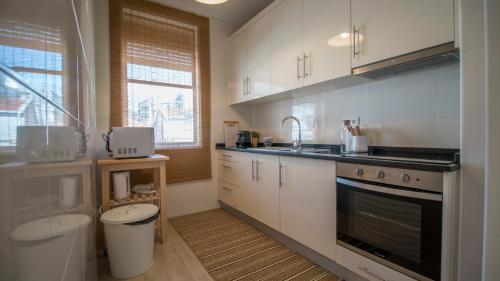 uma cozinha com armários brancos, um lavatório e um WC em DA'HOME - Marquês Lovely 2BD Apartment no Porto