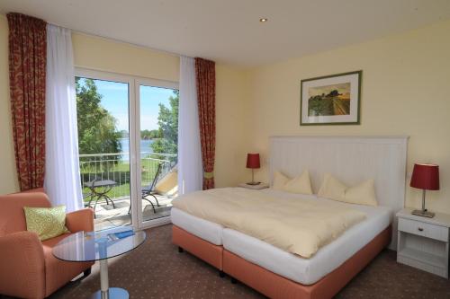 um quarto de hotel com uma cama e uma varanda em Strandhaus am Inselsee em Güstrow