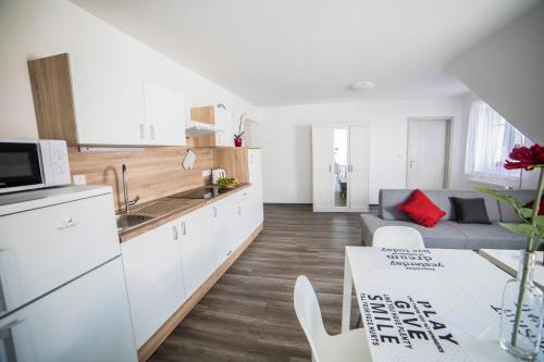 a kitchen and living room with white cabinets and a table at Apartmány U parku Třeboň in Třeboň
