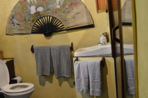 a bathroom with a toilet and a sink and towels at Treetops B & B Inn in San Juanillo