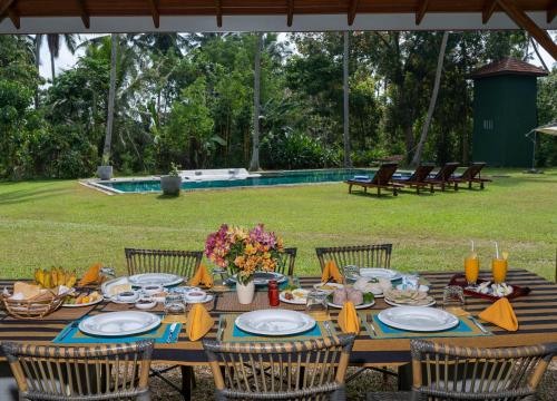 een houten tafel met stoelen en eten erop bij Garden Villa Ronnaduwa in Hikkaduwa