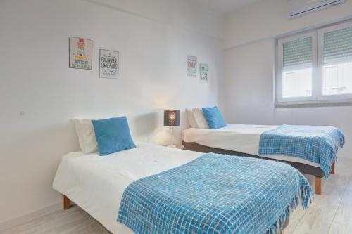リスボンにあるMouraria House Central and Quiet with a Balconyのベッド2台(青と白のシーツ付)が備わる客室です。