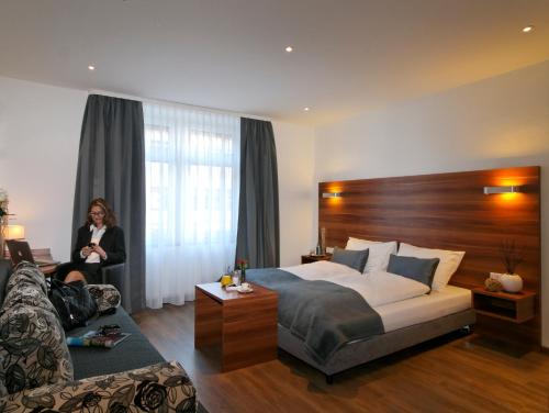 a woman in a hotel room with a bed and a couch at Schlotzeria Hotel I Café I Eis in Grenzach-Wyhlen
